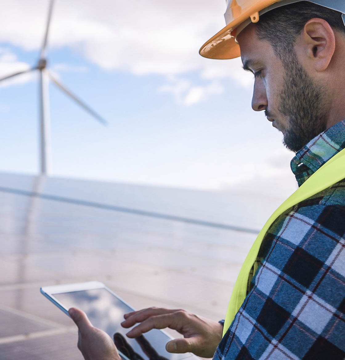 Engineer working on a tablet at a solar and wind farm